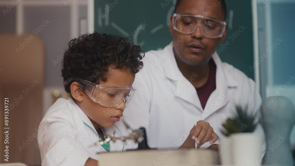 Little boy and dad growing bacteria in a petri dish, conducting lab experiment Little boy and dad growing bacteria in a petri dish, conducting lab experiment
