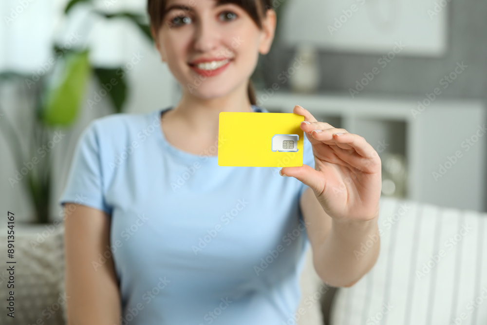 Woman holding SIM card at home, selective focus Woman holding SIM card at home, selective focus
