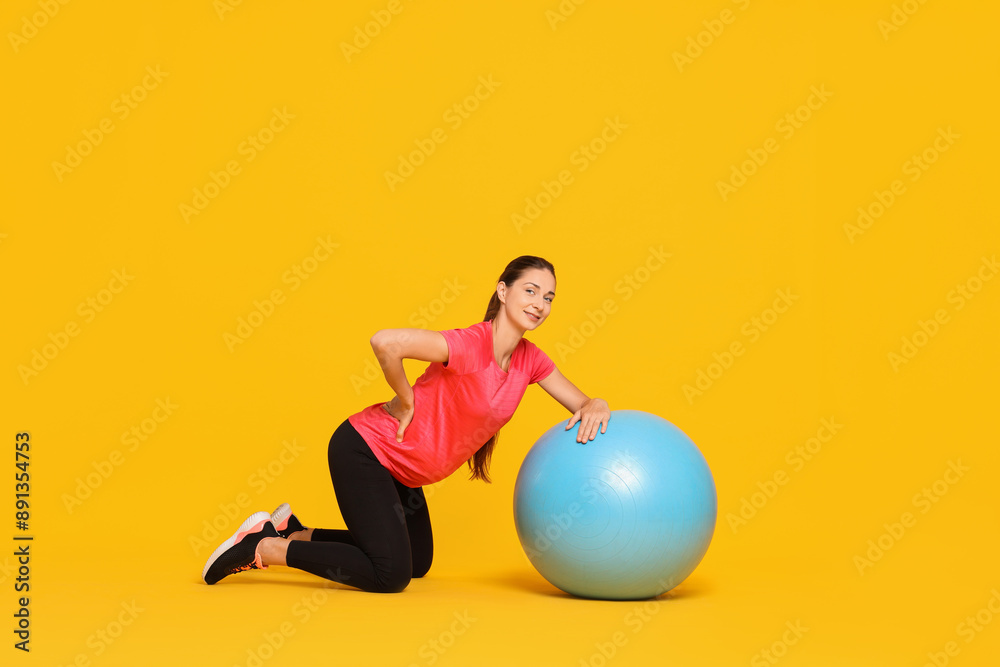 Beautiful pregnant woman doing exercises with fitball on yellow background Beautiful pregnant woman doing exercises with fitball on yellow background