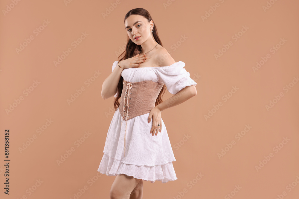 Fototapeta premium Beautiful woman in velvet corset posing on beige background