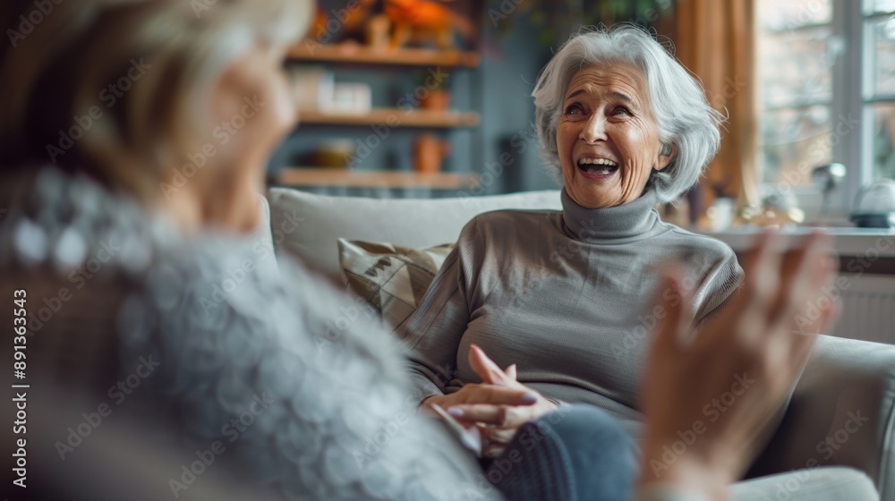 Two women are sitting on a couch, one of them is smiling Two women are sitting on a couch, one of them is smiling