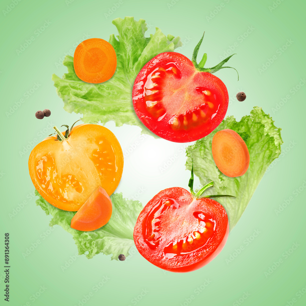 Naklejka premium Cut tomatoes, carrot, lettuce and allspice in air on green gradient background