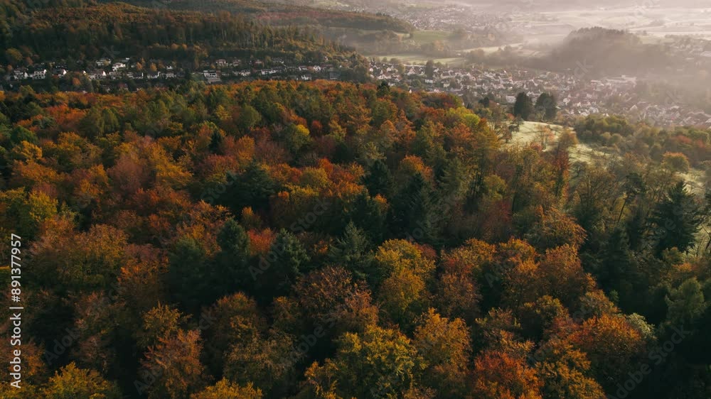 Flying over a colorful forest and a town in autumn. Aerial smooth footage with gorgeous fall colors 