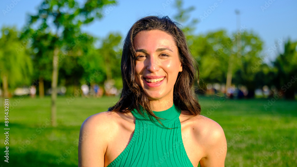 A young brunette woman laughs looking at the camera in a scenic park A young brunette woman laughs looking at the camera in a scenic park