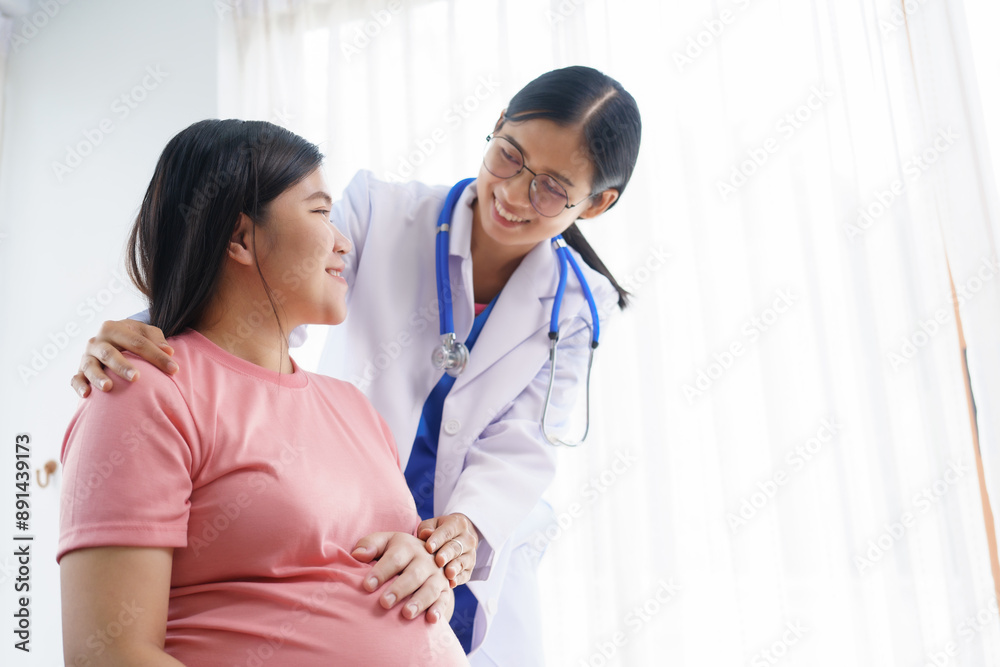 A pregnant woman sits on the sofa in the clinic. The doctor examines her abdomen and reviews the ultrasound results. Offering encouragement, the doctor holds her hand, providing support and care.