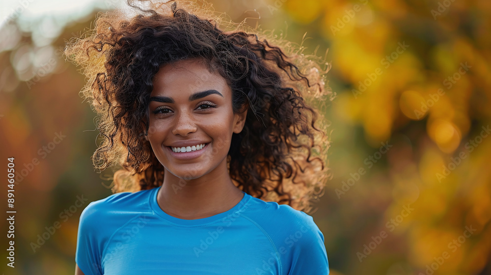 A young athletic woman with curly hair in a blue sports T-shirt in an autumn park A young athletic woman with curly hair in a blue sports T-shirt in an autumn park