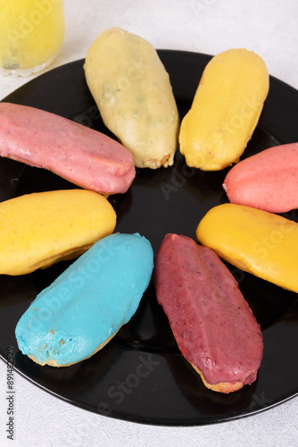 A close-up of colorful éclairs perfect for food blogs, recipe websites, and social media. The éclairs are arranged in a circular pattern on a black plate, creating a visually appealing image. photo