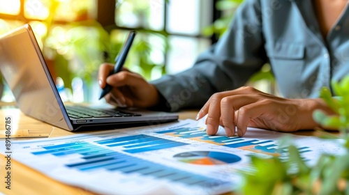 A focused individual analyzing business graphs and charts on a laptop, emphasizing productivity in a modern workspace.