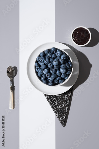 Arándanos en un recipiente blanco y mermelada de arándanos sobre un fondo gris y blanco. Vista superior	