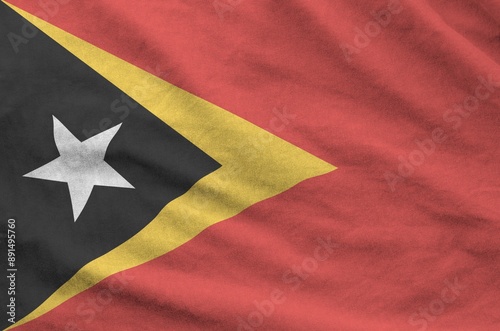 Timor Leste flag depicted on folded wavy fabric of old cloth close up photo