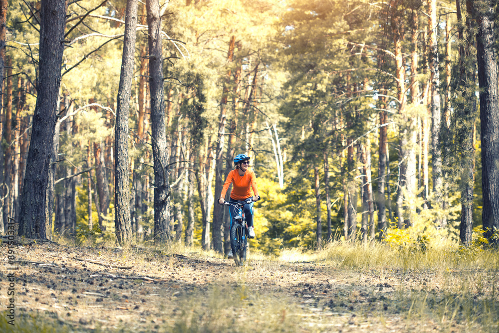 woman cyclist rides in the forest on a mountain bike. woman cyclist rides in the forest on a mountain bike.
