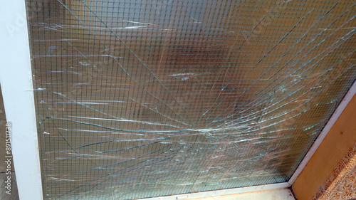 Photos Close-up view of broken windowpane with a wire mesh behind it