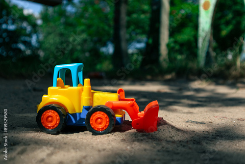 Small colorful toy bulldozer on the sand 