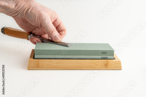 man woman flattening the back of a chisel blade on a whetstone