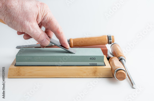 man woman tradesperson  sharpening the bevel of a chisel blade on a whetstone photo