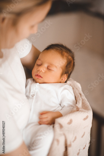 Mother holding infant baby boy 1-2 months old sleeping on hands in room. Motherhood.