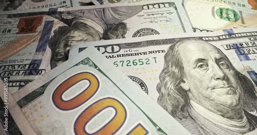 One hundred dollar bills, close up. Lot of cash American dollars lie chaotically on surface, smooth movement. Dollars, bucks, cash, hundred dollar bills, money for investment and profit, copy space.