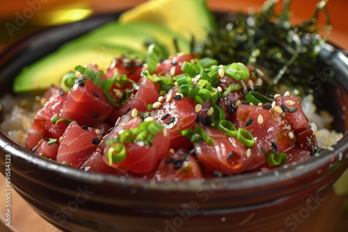 A bowl of poke, featuring diced raw tuna, avocado, and seaweed salad, served over a bed of sushi rice and drizzled with soy sauce © Nico