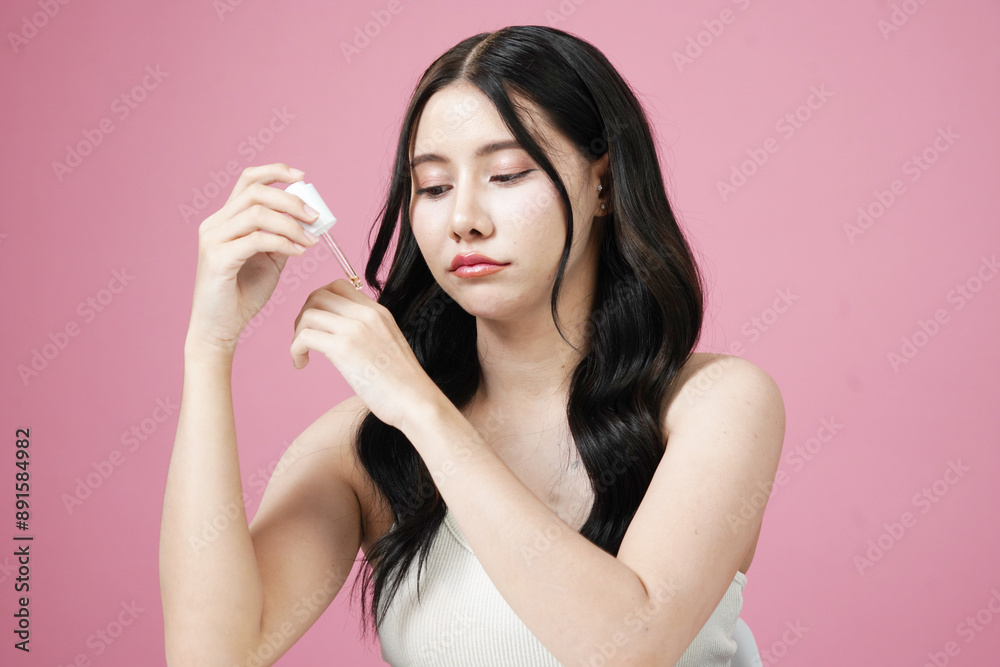 Young beautiful Asian woman with fresh, natural facial skin holding cosmetics, trial serum tube, happy smile, pink background.
Young beautiful Asian woman with fresh, natural facial skin holding cosmetics, trial serum tube, happy smile, pink background.