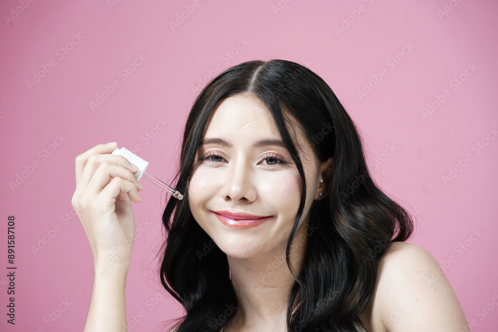 Young beautiful Asian woman with fresh, natural facial skin holding cosmetics, trial serum tube, happy smile, pink background.
Young beautiful Asian woman with fresh, natural facial skin holding cosmetics, trial serum tube, happy smile, pink background.