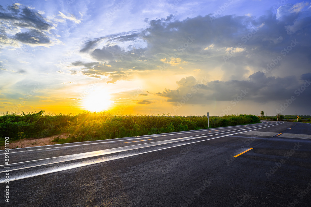 Fototapeta premium Wet asphalt road after rain in countryside at sunset, with a beautiful sky, and rain clouds