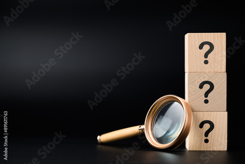 Magnifying glass and stack of question mark wood cubes, analyze the questions, FAQs, and questions that need the answer 