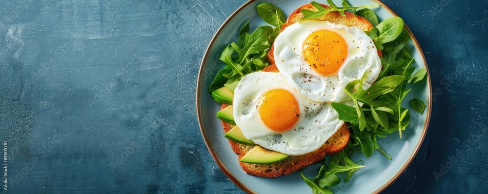 Healthy breakfast with fried eggs, avocado, and greens on toasted bread, served on a plate with blue background. Healthy breakfast with fried eggs, avocado, and greens on toasted bread, served on a plate with blue background.