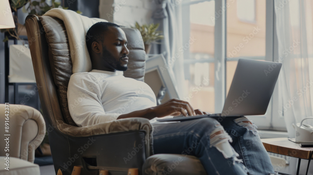 Man relaxing in a comfortable chair using a laptop in a cozy living room bathed in natural sunlight. Man relaxing in a comfortable chair using a laptop in a cozy living room bathed in natural sunlight.