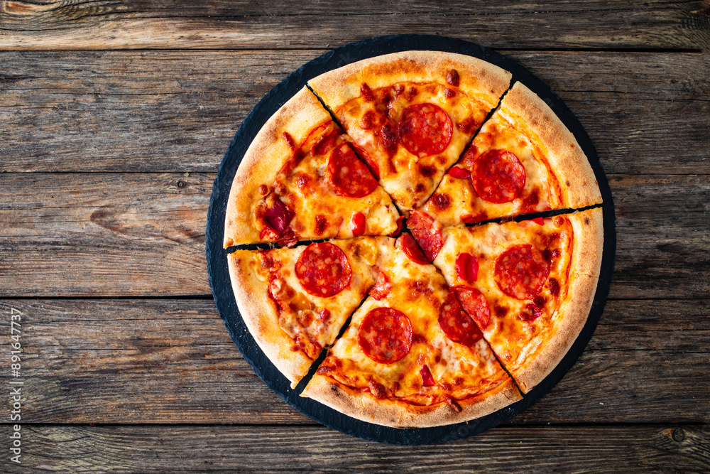 Circle pizza chorizo and mozzarella served on stony black plate on wooden table
Circle pizza chorizo and mozzarella served on stony black plate on wooden table