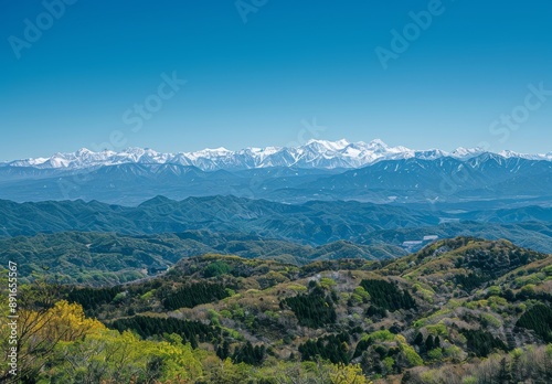 mountain range from an angle, clear blue sky, distant snow-capped mountains in background © Cetin
