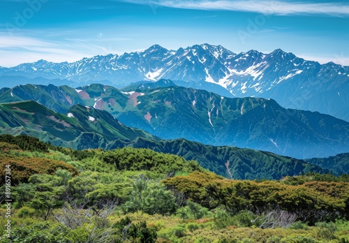 mountain range from an angle, clear blue sky, distant snow-capped mountains in background