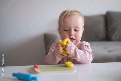  smiling little toddler working with plasticine in art and craft 