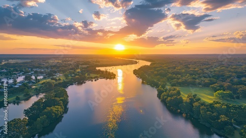 Present an aerial view of a river during sunset, with the sky painted in vibrant hues of orange and pink.