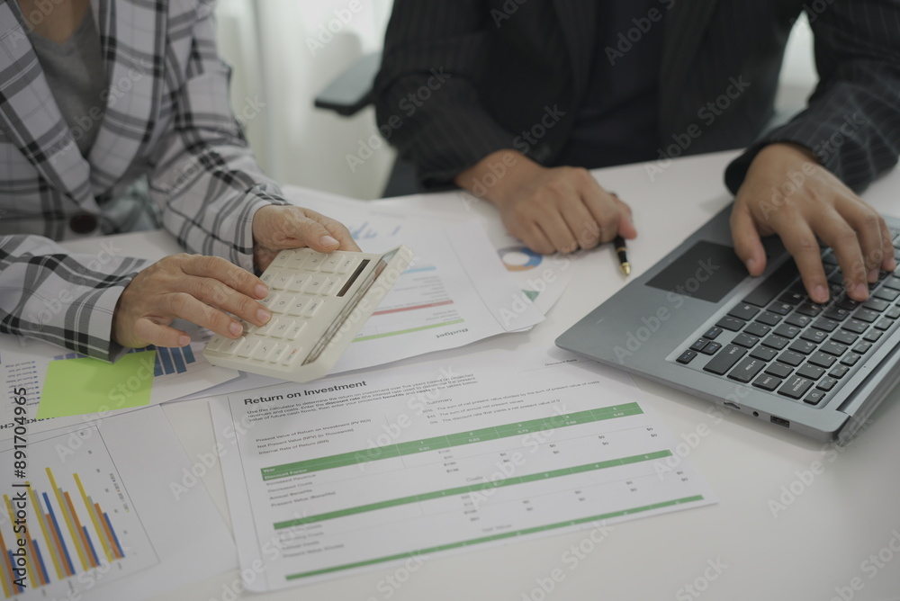Two businessmen meeting to analyze financial reports with tablet on paper on table and analyze the power dashboard display. on your tablet screen for business insights