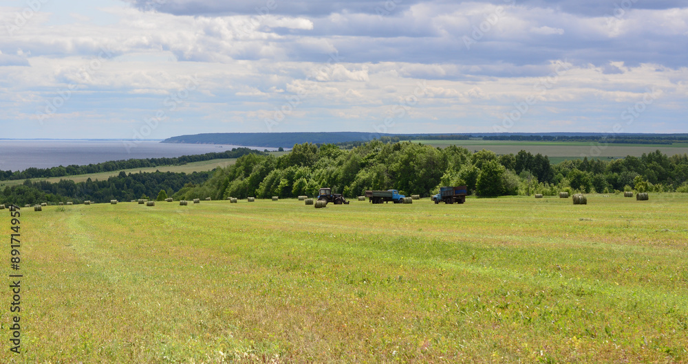 a field with tractors, haybales and a blue sky with a few clouds a field with tractors, haybales and a blue sky with a few clouds