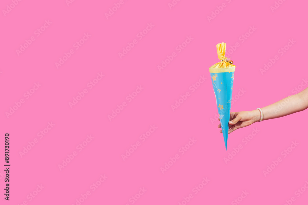 School cones in child hands on light pink background School cones in child hands on light pink background