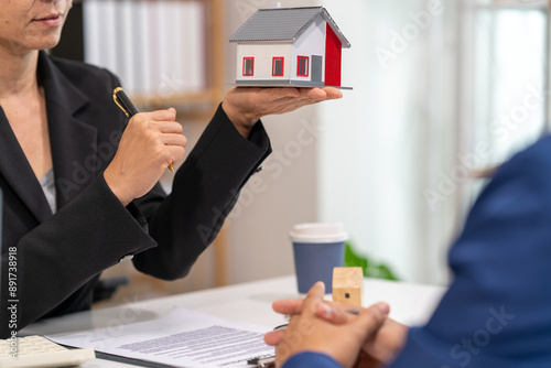 A real estate agent talks with his client regarding a home purchase contract, concept for real estate, moving house or renting property.