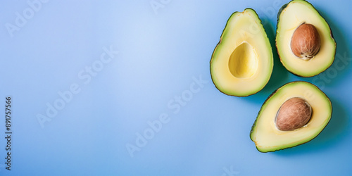 Avocado Halfes Pattern Blue Background: Three Avocado Halfes with Seeds on Light Blue Surface - Minimalist Healthy Food Concept with Copy Space photo