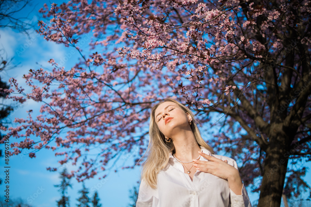 Woman with cherry flowers surrounded by blossoming trees copy space. Beauty and seasonal change and spring bloom season concept. Woman with cherry flowers surrounded by blossoming trees copy space. Beauty and seasonal change and spring bloom season concept.