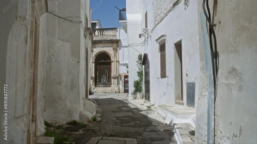 A narrow alleyway in ostuni, puglia, italy, showcasing charming whitewashed walls, rustic buildings, and a beautiful doorway under a bright blue sky. A narrow alleyway in ostuni, puglia, italy, showcasing charming whitewashed walls, rustic buildings, and a beautiful doorway under a bright blue sky.