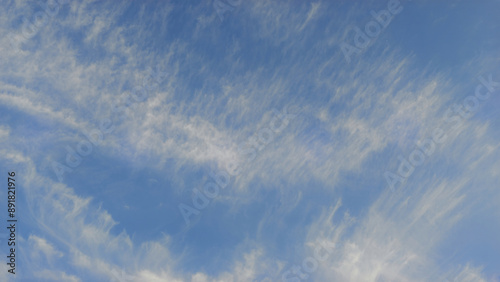 Expansive blue sky with delicate white clouds, creating a serene and open atmosphere.