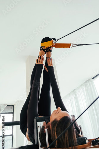 Mature woman doing Pilates exercise on pilates reformer bed 