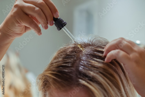 Unrecognised woman applies oil to her hair with pipette. Beauty caring for scalp and hair