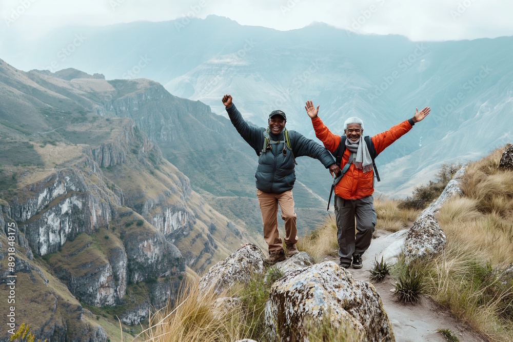 Obraz premium Two elderly men hiking in the mountains, arms raised in celebration. Concept for achievement, friendship, and adventure, suitable for promoting outdoor activities and a vibrant lifestyle in aging