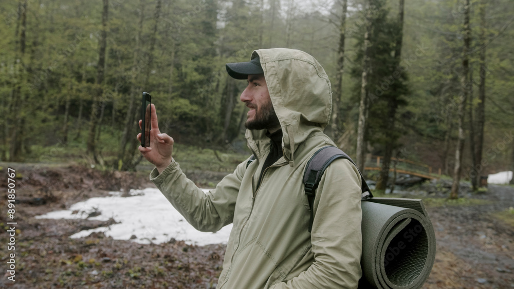 Adventurous camper man makes a video call with his mobile phone in the forest.
Adventurous camper man makes a video call with his mobile phone in the forest.