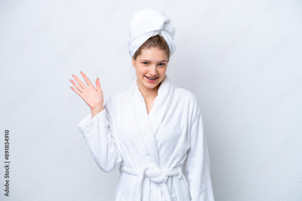 Teenager Russian girl in a bathrobe isolated on white background saluting with hand with happy expression Teenager Russian girl in a bathrobe isolated on white background saluting with hand with happy expression