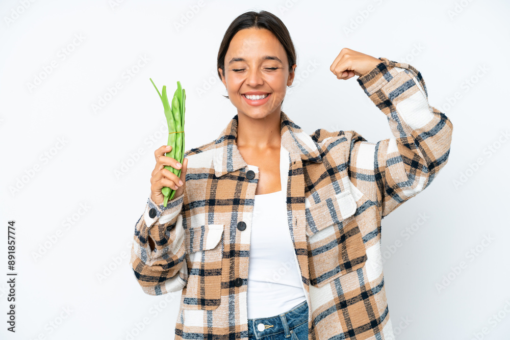 Young hispanic woman holding a green beans isolated on white background doing strong gesture Young hispanic woman holding a green beans isolated on white background doing strong gesture