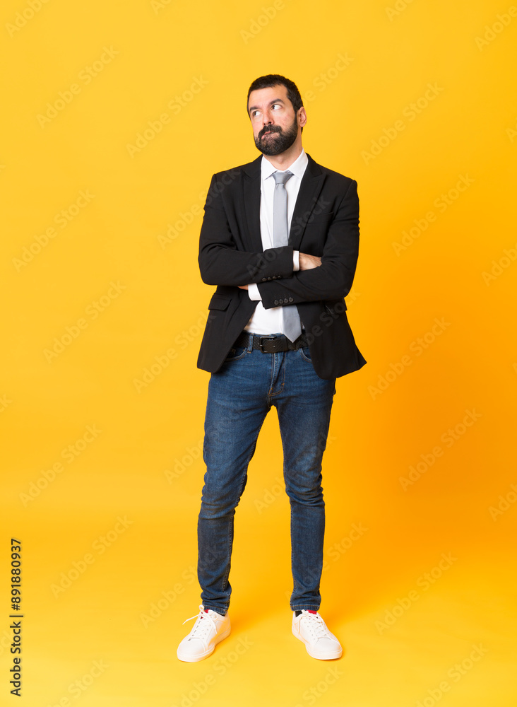 Full-length shot of business man over isolated yellow background with confuse face expression Full-length shot of business man over isolated yellow background with confuse face expression