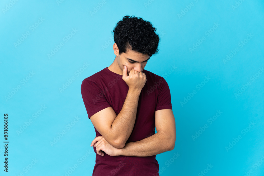 Young Venezuelan man isolated on blue background having doubts Young Venezuelan man isolated on blue background having doubts