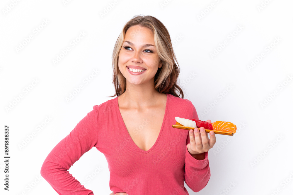 Young Russian girl holding sashimi isolated on white background posing with arms at hip and smiling